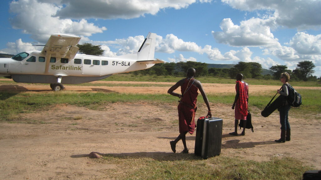 Ciara waiting for a plane at Masai Mara holding film equipment