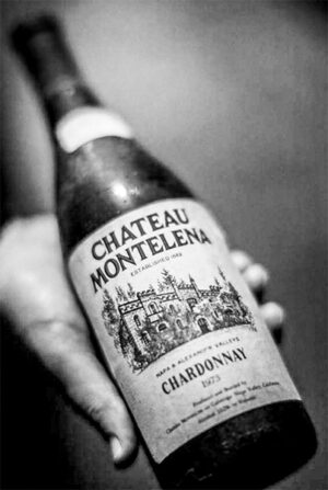 Black-and-white close-up of a hand holding a bottle of 1973 Chateau Montelena Chardonnay, the wine that won the white wine category at the historic Judgment of Paris tasting in 1976.
