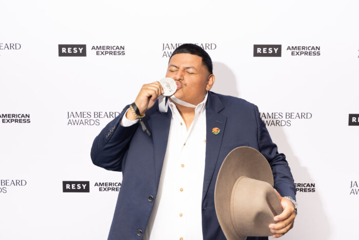 Chef Adrian Torres celebrates his 2026 James Beard Emerging Chef Award by kissing his medal while holding his signature cowboy hat. Torres, executive chef of Maximo in Texas, delivered one of the evening's most memorable acceptance speeches highlighting his immigrant journey and the evolving face of American cuisine.