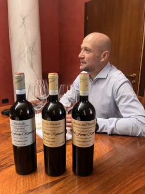 Marco Dal Forno of Dal Forno Romano sits at a tasting table surrounded by bottles of Valpolicella and Amarone wines. The intimate setting captures a professional tasting session, emphasizing the winery’s focus on craftsmanship and meticulous wine production.