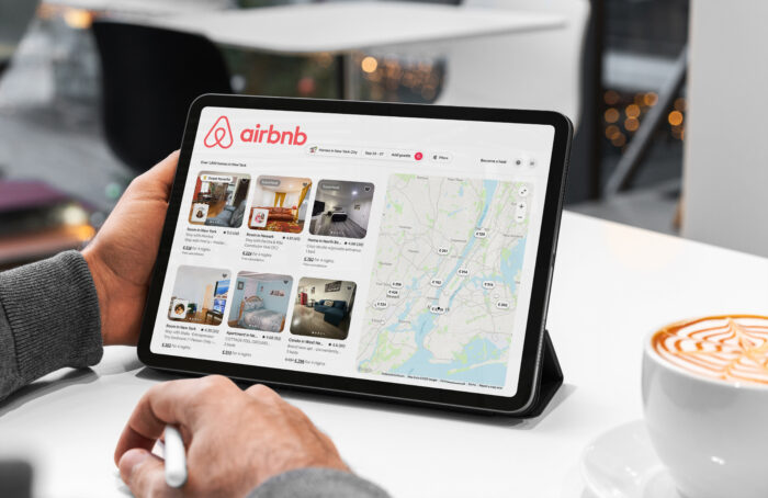 Businessman browsing airbnb listings on tablet in new york cafe, planning his next business trip
