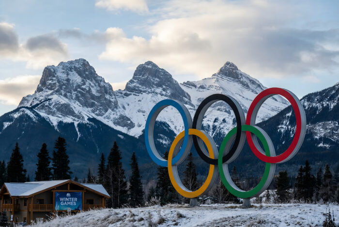 Olympic Rings Monument Against Snowy Mountains and Winter Games Building Keywords: olympic rings