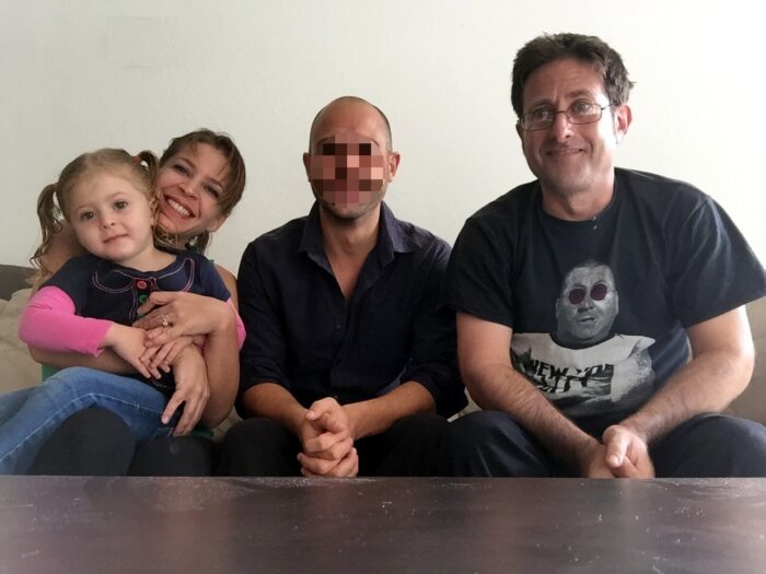 Corey Levitan, his wife, and his daughter sit together on a couch in a living room with the unexpected Airbnb roomate.