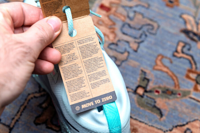 Paris, France - Jan 11, 2026: Close-up POV of hand holding Nike footwear product label with recycling information and Move to Zero sustainability text. Unboxing new athletic shoes.
