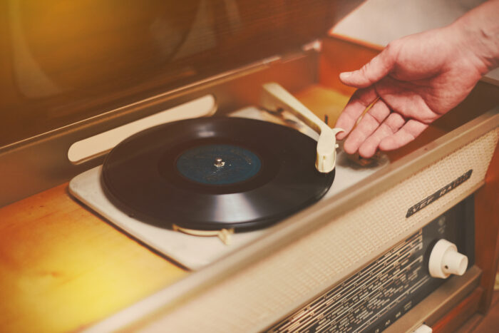 Vinyl record, spinning on turntable, Vintage record player with radio 60's. Male hand placing the needle on vinyl record