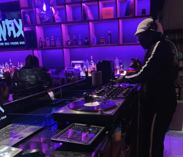 DJ spinning vinyl behind the bar at WAX Vinyl Bar and Ramen Shop.