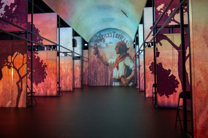Immersive literary exhibition with colorful illuminated panels and a projection of Gulliver’s Travels in a contemporary gallery space.